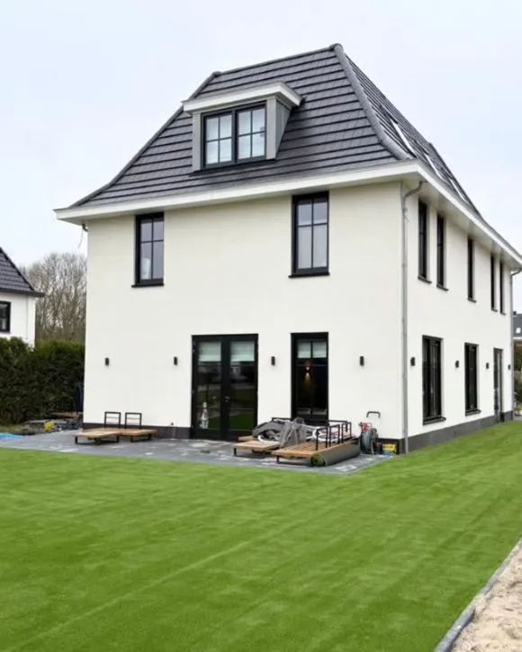 Aangelegd kunstgrastuin met strak gazon bij een moderne nieuwbouwwoning