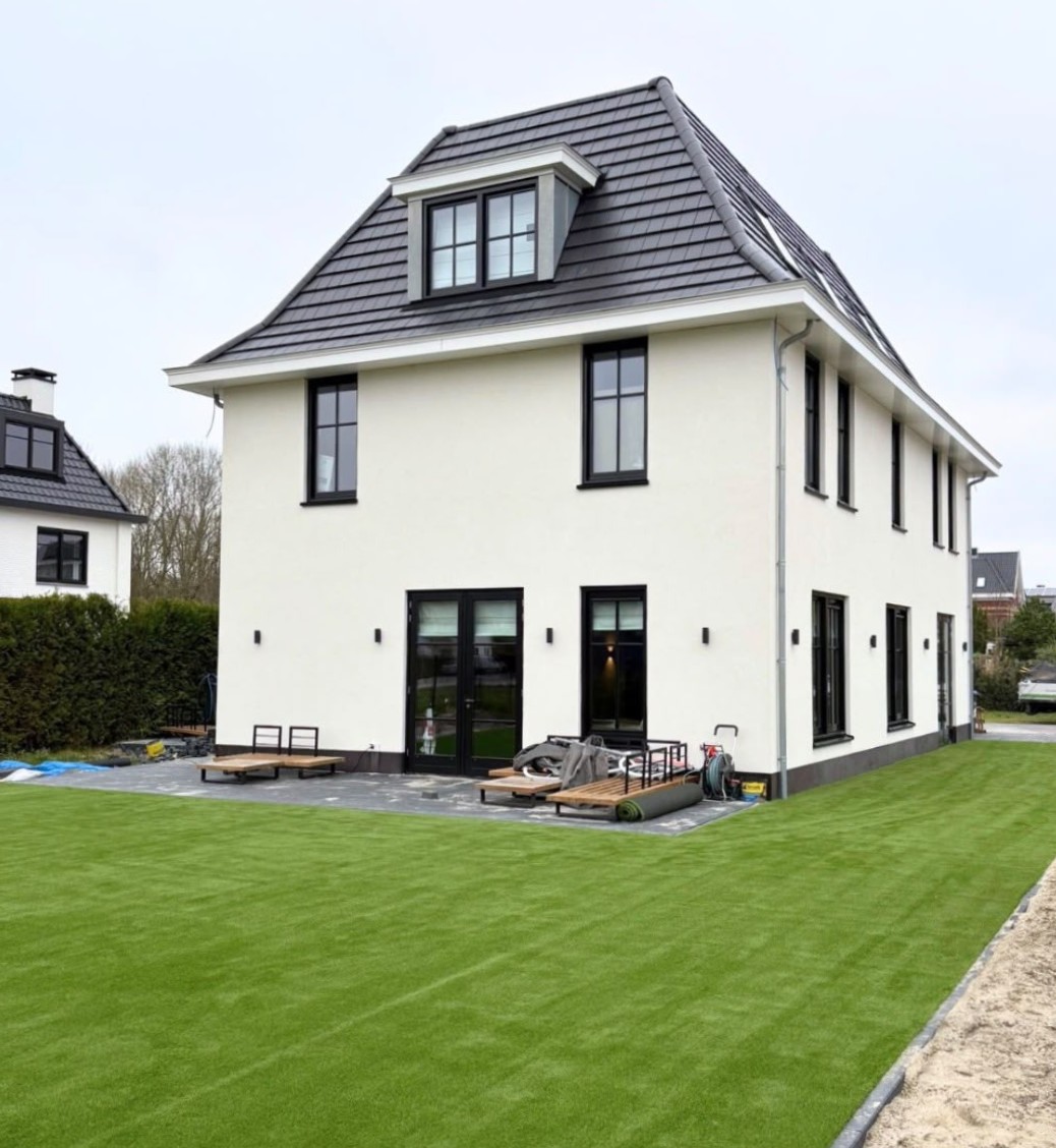 Aangelegd kunstgrastuin met strak gazon bij een moderne nieuwbouwwoning